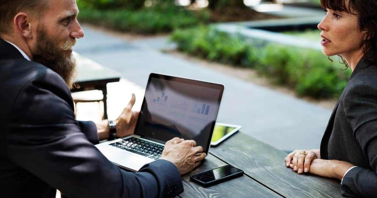 Two business partners reviewing company details on a laptop